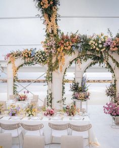 an outdoor wedding setup with flowers and greenery on the walls, tables and chairs