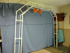 a white metal frame with two pumpkins hanging from it's sides in a room