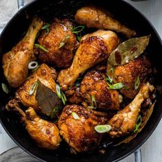 a skillet filled with chicken wings and garnished with herbs