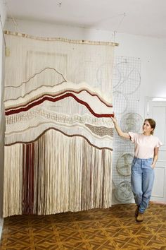 a woman standing in front of a wall hanging