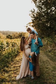 a family standing in the grass with one holding their child and looking at each other