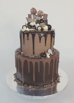 a three tiered chocolate cake with white frosting and decorations on the top layer