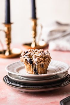 a muffin sitting on top of a white plate next to two silver candlesticks