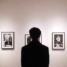 a person standing in front of pictures on the wall with their back to the camera