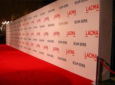 a red carpeted wall with the name lacma written on it at an event