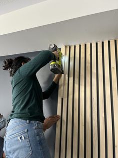 a woman sanding wood on the side of a wall