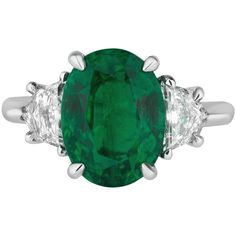 an oval emerald and diamond ring with three diamonds on each side, set in white gold