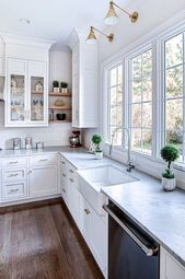 a kitchen with white cabinets and green trim around the window, along with a dishwasher