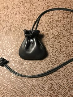 a small black purse sitting on top of a brown leather couch next to a cord