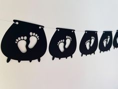 a line of black paper cutouts with footprints hanging from it's sides on a string