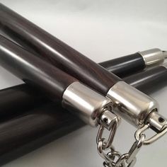 two pens with chains attached to them on a white surface, one is black and the other is silver