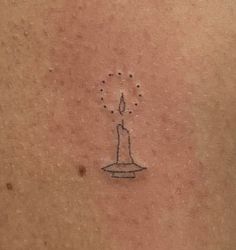 a small candle tattoo on the back of a woman's shoulder