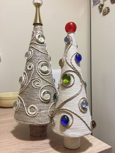 two small christmas trees sitting on top of a wooden table