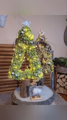 a christmas tree made out of branches with lights in the shape of a letter and an animal figurine