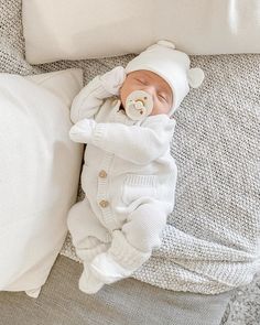 a baby laying on top of a bed next to pillows