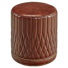 a brown leather stool with braiding on the bottom and nail - studded edges