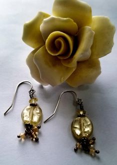 These luminous foil lined German lamp work glass earrings appear to be lit from within! The palest shimmering jonquil yellow flat ovals remind me of fireflies on a childhood summer day! These delicate little beauties are accented with Bali sterling silver daisy spacers, vintage jonquil Swarovski crystals, and finished with a trio of teeny citrine dangle drops. The ear wires are sterling silver hooks, which will come with clear rubber stoppers to keep them secure on the ear lobe. These one-of-a-k Gold Wire Wrapped Glass Earrings, Elegant Yellow Wire Wrapped Earrings, Vintage Gold Glass Earrings, Yellow Glass Earrings For Gift, Gold Czech Glass Earrings For Party, Party Gold Earrings With Czech Glass, Elegant Glass Crystal Earrings For Gift, Elegant Crystal Glass Earrings For Gifts, Elegant Yellow Czech Glass Jewelry