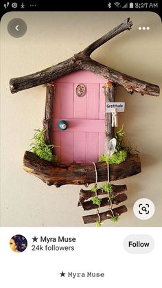 a pink house made out of wood and moss on top of a tree branch with stickers attached to it