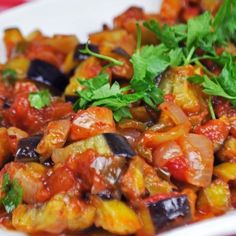 a white plate topped with vegetables covered in sauce