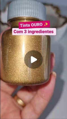 a hand holding a gold colored jar with the words tinta ouro com 3 ingredients