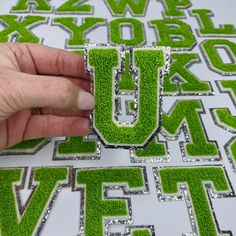 a hand is holding the letters made out of grass