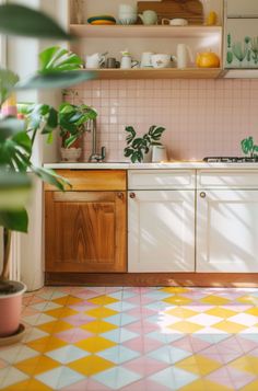 a kitchen with yellow and pink tiles on the floor, potted plant in the corner