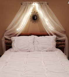 a bed with white comforter and pillows under a canopy over the top of it