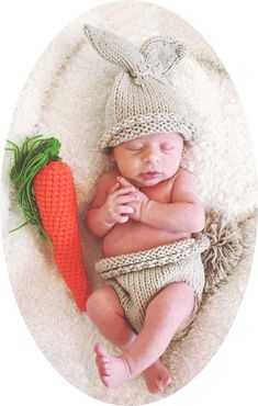 a baby is wearing a knitted bunny outfit and holding a carrot