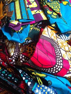 a pile of colorful scarves with different designs on them, all piled up together