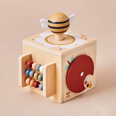 a wooden toy with a bee on top and an apple in the middle sitting inside it