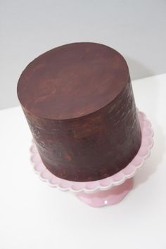 a chocolate cake sitting on top of a pink plate with scalloped trimming