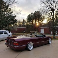 a maroon convertible parked in front of a white car