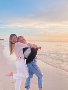 two women standing on the beach hugging each other