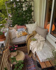 a balcony with lots of plants and pillows on it