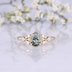 a close up of a ring on a white surface with flowers in the back ground