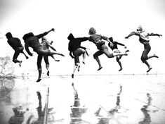 five people jumping in the air with their legs spread out and one person wearing a hat