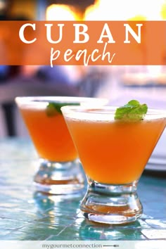 two glasses filled with orange drinks sitting on top of a table