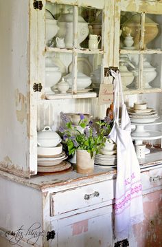 an old china cabinet filled with dishes and flowers