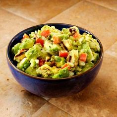 a blue bowl filled with guacamole on top of a tile countertop