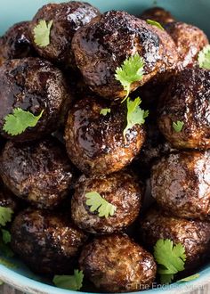 a blue bowl filled with meatballs and garnished with cilantro leaves