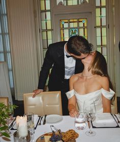 a man and woman kissing at a dinner table