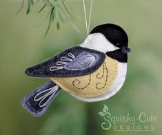 a bird ornament hanging from a branch with the words chickade on it