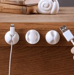 a person is plugging in to an ipod charger on a wooden table next to books