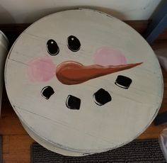 a painted snowman face sitting on top of a wooden table