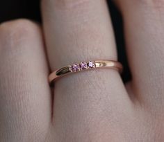 a woman's hand with a pink diamond ring on her left hand and the other hand holding it