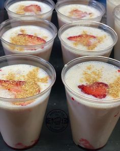 there are many desserts in plastic cups on the table with strawberries and crumbs