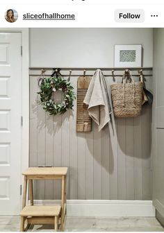 a wooden bench sitting next to a wall with two coats hanging on it's hooks