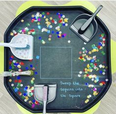 a black tray with confetti, measuring spoons and spatulas on it