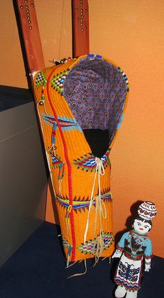 an orange bag with skis on it next to a small doll