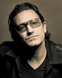 a man wearing glasses and a black shirt is looking at the camera while he looks off to the side